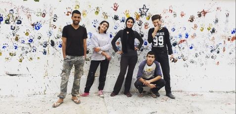 A volunteer and her students paint a wall in Moulay Idriss.